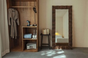 A wooden wardrobe with a robe, a small shelf with books and a lamp, and a large mirror with a wooden frame. - Modern Luxe 3BR Villa in La Privada Private Pool Exclusive Beach Club Concierge (Tulum)