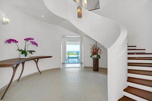 Ein modernes Interieur mit einer geschwungenen Treppe, einer Holzbank und zwei Blumentöpfen.