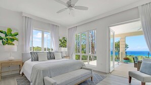 A bedroom with a bed, a nightstand, a chair, and a view of the ocean. - Contemporary 6BR Villa Sea Views Infinity Pool Resort Access (Montego Bay)
