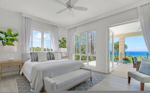 Ein Schlafzimmer mit Bett, Nachttisch, Stuhl und Meerblick.