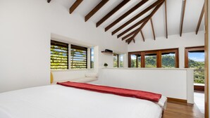 A bedroom with a large bed, wooden beams on the ceiling, large windows, and a balcony with a view. - Hidden 4BR Gem Pool Nature Escape in the Hills of Port Antonio (Port Antonio)