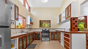 A kitchen with a built-in oven, a sink, and wooden cabinets. - Hidden 4BR Gem Pool Nature Escape in the Hills of Port Antonio (Port Antonio)