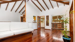 A spacious room with a wooden bench, a potted plant, and a view of a kitchen area. - Hidden 4BR Gem Pool Nature Escape in the Hills of Port Antonio (Port Antonio)