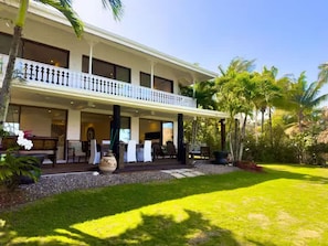Ein zweistöckiges Hotel mit überdachter Terrasse und gepflegtem Rasen.