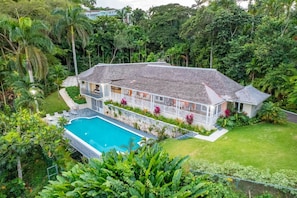 A house with a swimming pool, surrounded by lush greenery and palm trees. - Secluded 3BR Garden Villa Pool Ocean Views (Sandy Bay)