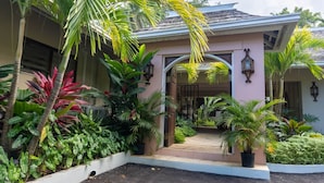 A house with a covered entrance, surrounded by lush tropical plants. - Secluded 3BR Garden Villa Pool Ocean Views (Sandy Bay)