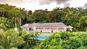 A two-story house with a swimming pool surrounded by lush greenery. - Secluded 3BR Garden Villa Pool Ocean Views (Sandy Bay)