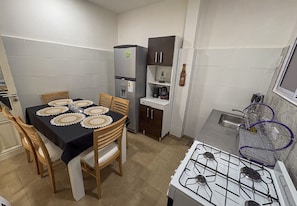 A compact kitchen with a gas stove, a refrigerator, and a dining table set with placemats. - Classic, spacious for up to 5 people near Plaza de Mayo and Casa Rosada (Buenos Aires)