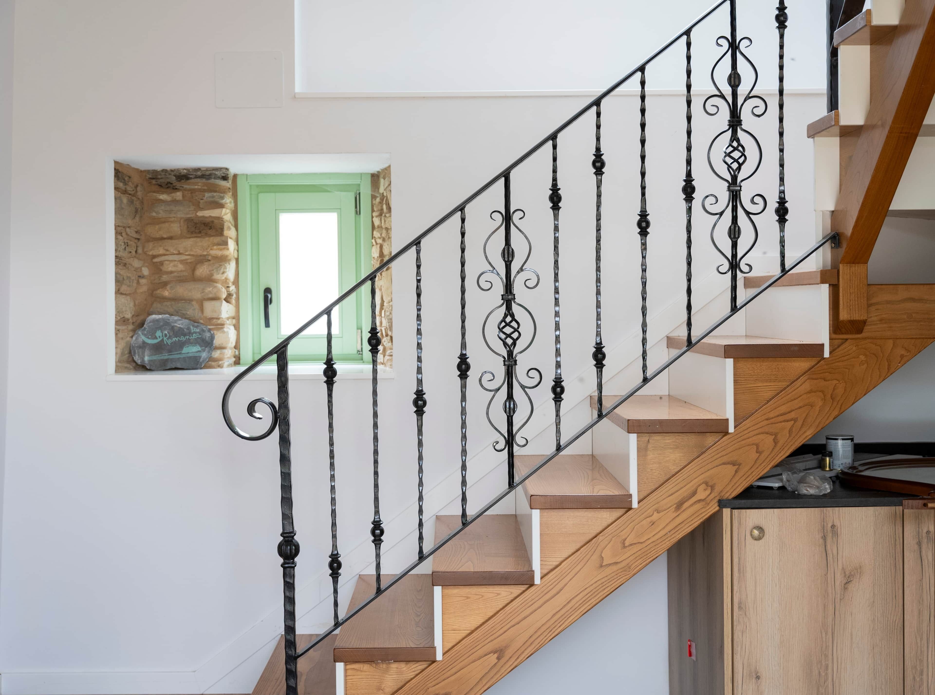Una escalera con barandilla de madera y balaustres negros.