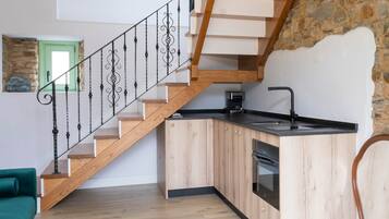Een moderne keuken met houten kastjes, een inbouwoven en een zwart aanrecht.