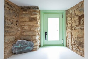 Un coin de mur en pierre avec une porte verte et une pierre sur laquelle sont gravés un bateau et du texte.