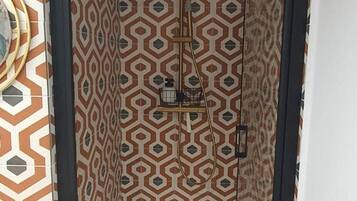 Eine Dusche mit Wandpaneelen in geometrischem Muster, einer Deckenleuchte und einem sichtbaren Bedienfeld.