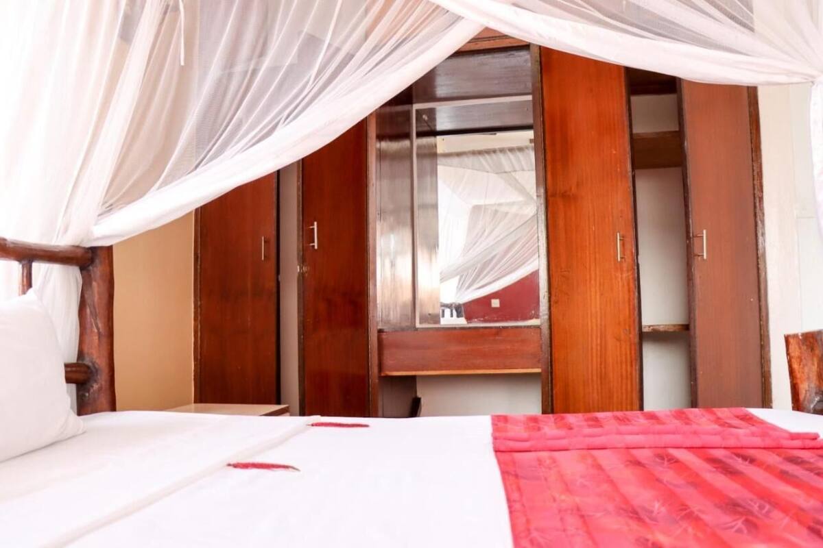A bedroom with a bed, a wardrobe, and a mirror.