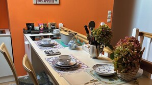 A dining area with a long table set for four, featuring a variety of tableware and a decorative wall hanging. - Lavender room with twin beds, long Zen infrared heating and softness (Étaples)