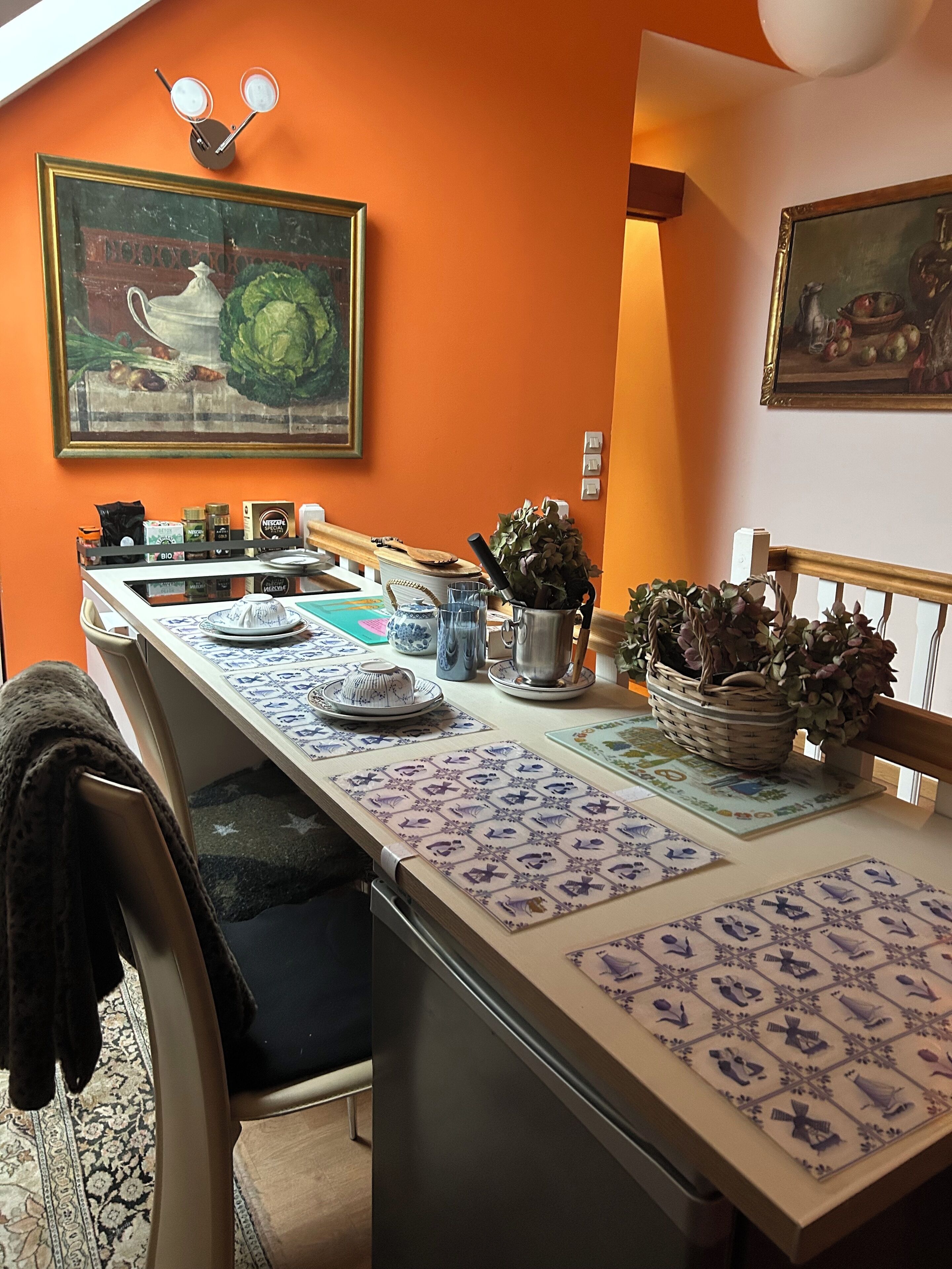 Una cocina con una encimera larga, distintos utensilios de cocina y dos lámparas fijadas a la pared.