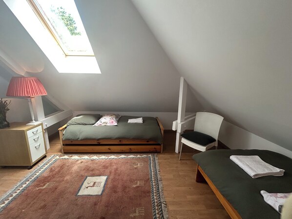 Une chambre à coucher avec un lit, une chaise, un bureau, une lampe et une fenêtre.