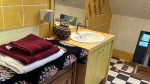 A bathroom with a checkered floor, a wooden vanity, a sink, and a mirror. - Lavender room with twin beds, long Zen infrared heating and softness (Étaples)