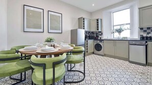 A modern kitchen with a dining area, built-in cabinets, a washing machine, and a large window. - Milton Apartment - 3 Beds, Kirkcaldy with sea view (Fife)