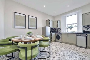 Eine moderne Küche mit Essbereich, Einbauküche, Waschmaschine und großem Fenster.