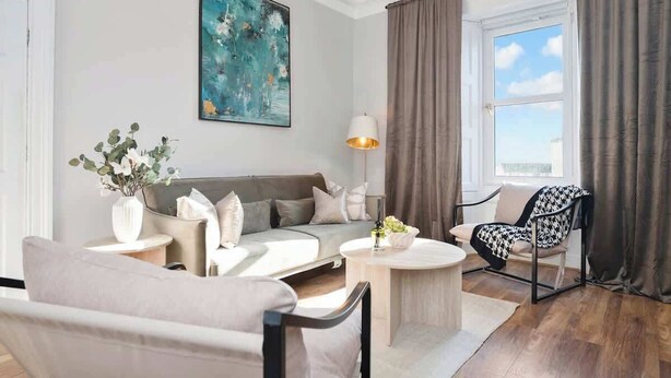 A modern living room with a sofa, armchairs, a coffee table, a lamp, and a painting on the wall. - Milton Apartment - 3 Beds, Kirkcaldy with sea view (Fife)