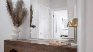 A wooden console table with a mirror, pampas grass, and books. - Milton Apartment - 3 Beds, Kirkcaldy with sea view (Fife)