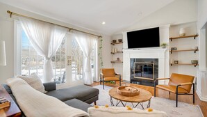 Ein modernes Wohnzimmer mit Kamin, bequemen Sitzmöglichkeiten und einem großen Fernseher.