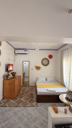 Una habitación de hotel con una cama, un aparador de madera, un televisor y un ventilador de techo.