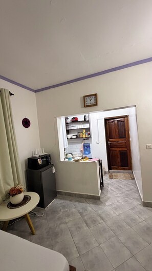 Un ambiente compatto con angolo cottura, un piccolo spazio pranzo e una porta che conduce in un'altra stanza.