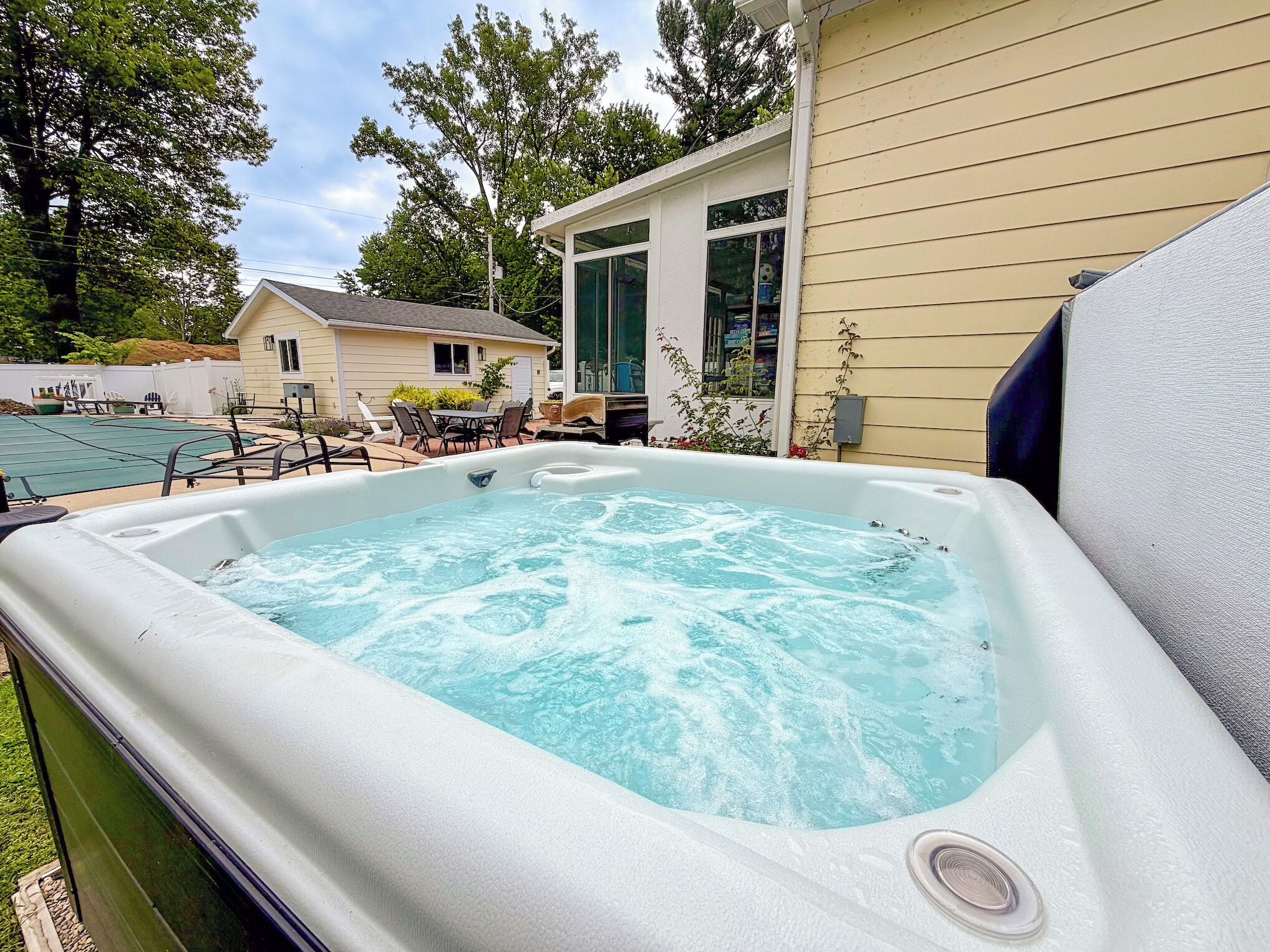 A hot tub in a backyard with a house in the background.