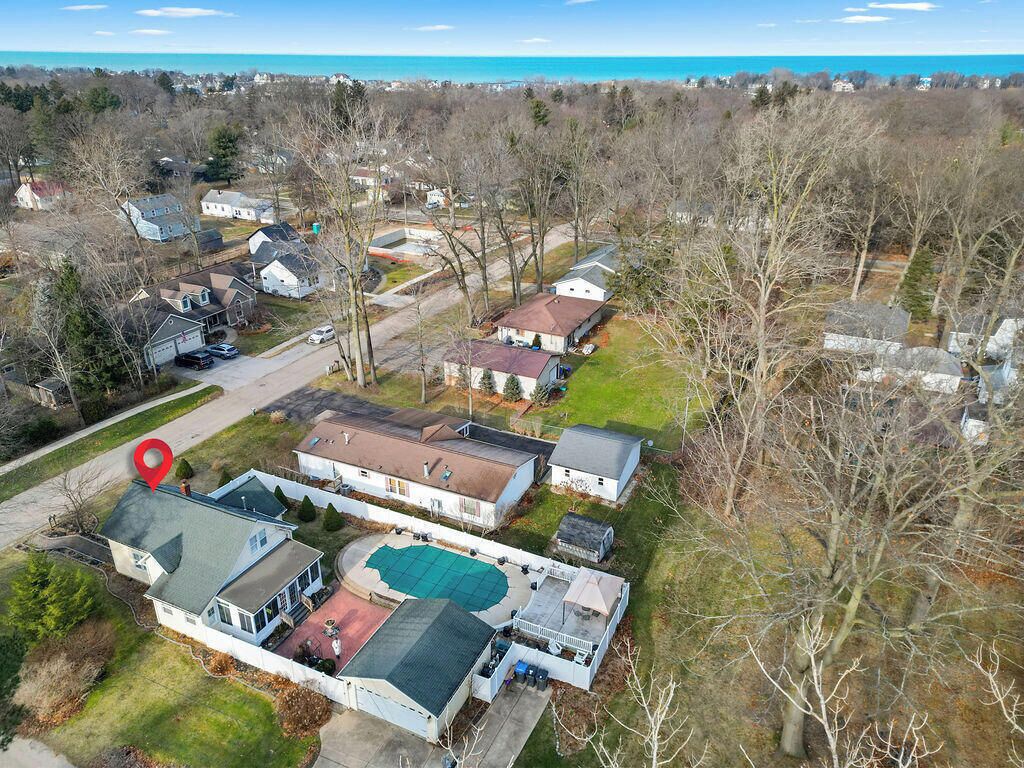 An aerial view of a residential area with houses, a swimming pool, and a red location marker.