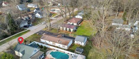 An aerial view of a residential area with houses, a swimming pool, and a red location marker.
