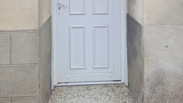 Una porta blanca amb una placa amb el número de l'adreça a la part superior.