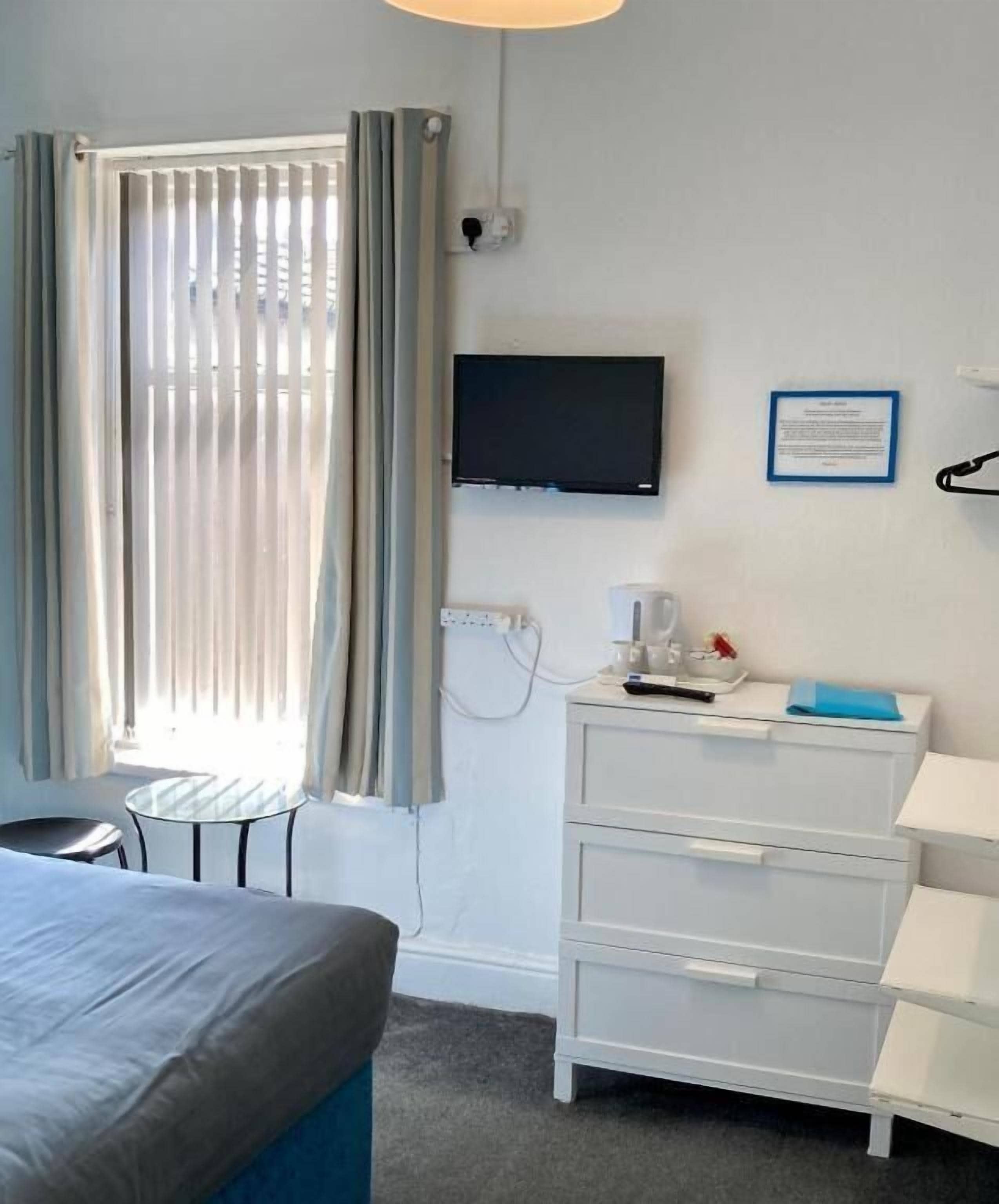Ein Hotelzimmer mit einem Bett, einem Schreibtisch, einem Sessel, einem Fernseher und einer Kommode.