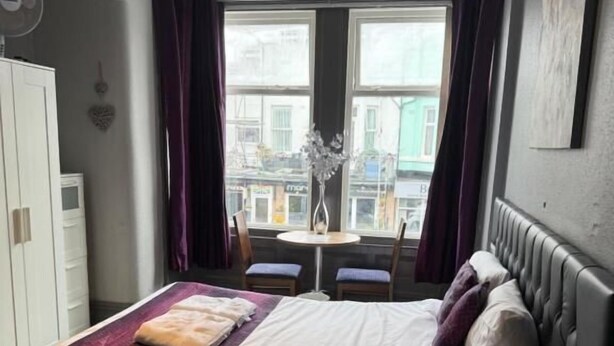Ein Schlafzimmer mit einem Bett, einem Nachttisch und einem Fenster mit Vorhängen.