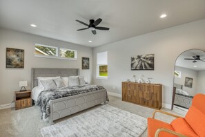 Un dormitorio con cama, cómoda de madera, espejo y ventilador de techo.