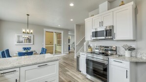 A modern kitchen with white cabinetry, stainless steel appliances, and a marble countertop. - Beautiful 3 bedroom house with views of the hills. (Salem)