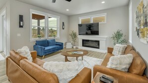 A living room with a blue sofa, brown leather chairs, a white fluffy rug, a fireplace, and a ceiling fan. - Beautiful 3 bedroom house with views of the hills. (Salem)