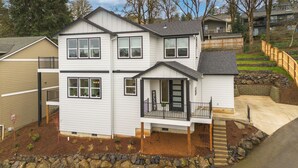 A two-story residential building with a front porch, a small deck, and a stone retaining wall. - Beautiful 3 bedroom house with views of the hills. (Salem)