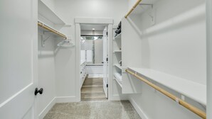 A narrow hallway with white walls, a wooden floor, and a door at the end leading to a bathroom. - Beautiful 3 bedroom house with views of the hills. (Salem)