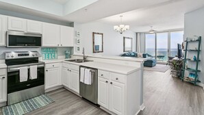 Een moderne keuken met witte kasten, een ingebouwde oven en een groot eiland met een spoelbak.