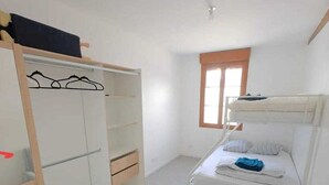 Ein kleines Schlafzimmer mit Bett, Kleiderschrank und einer Sitzecke.