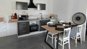 Eine moderne Küche mit Einbauofen, Mikrowelle und Spüle. Es gibt einen Essbereich mit einem Holztisch und weißen Stühlen.