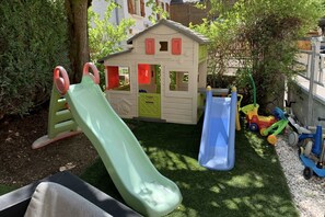 A children's play area with a slide, a small house, and toy vehicles.