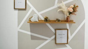 Een muur met een geometrisch patroon, een houten plank met decoratieve objecten en een lijst met tekst.