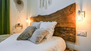 Een bed met een houten hoofdbord, een wandlamp en een stopcontact.