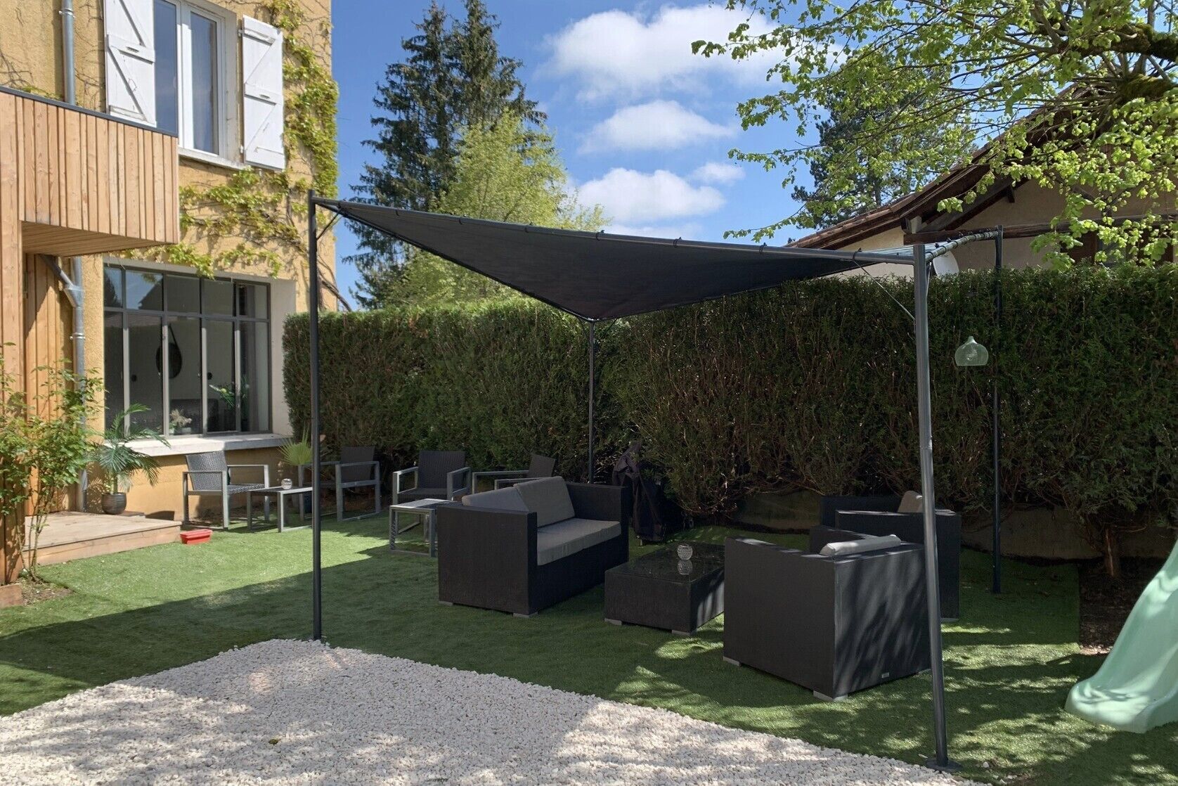 A patio with outdoor furniture, a shaded area, and a grassy lawn.