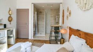 Une chambre comprenant un lit, un bureau, un espace douche et une petite table avec des tabourets.