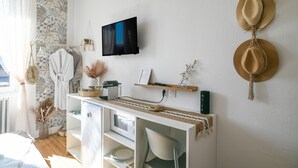 Une chambre comprenant un lit, un téléviseur fixé au mur, un bureau avec un ordinateur et un porte-chapeaux fixé au mur.