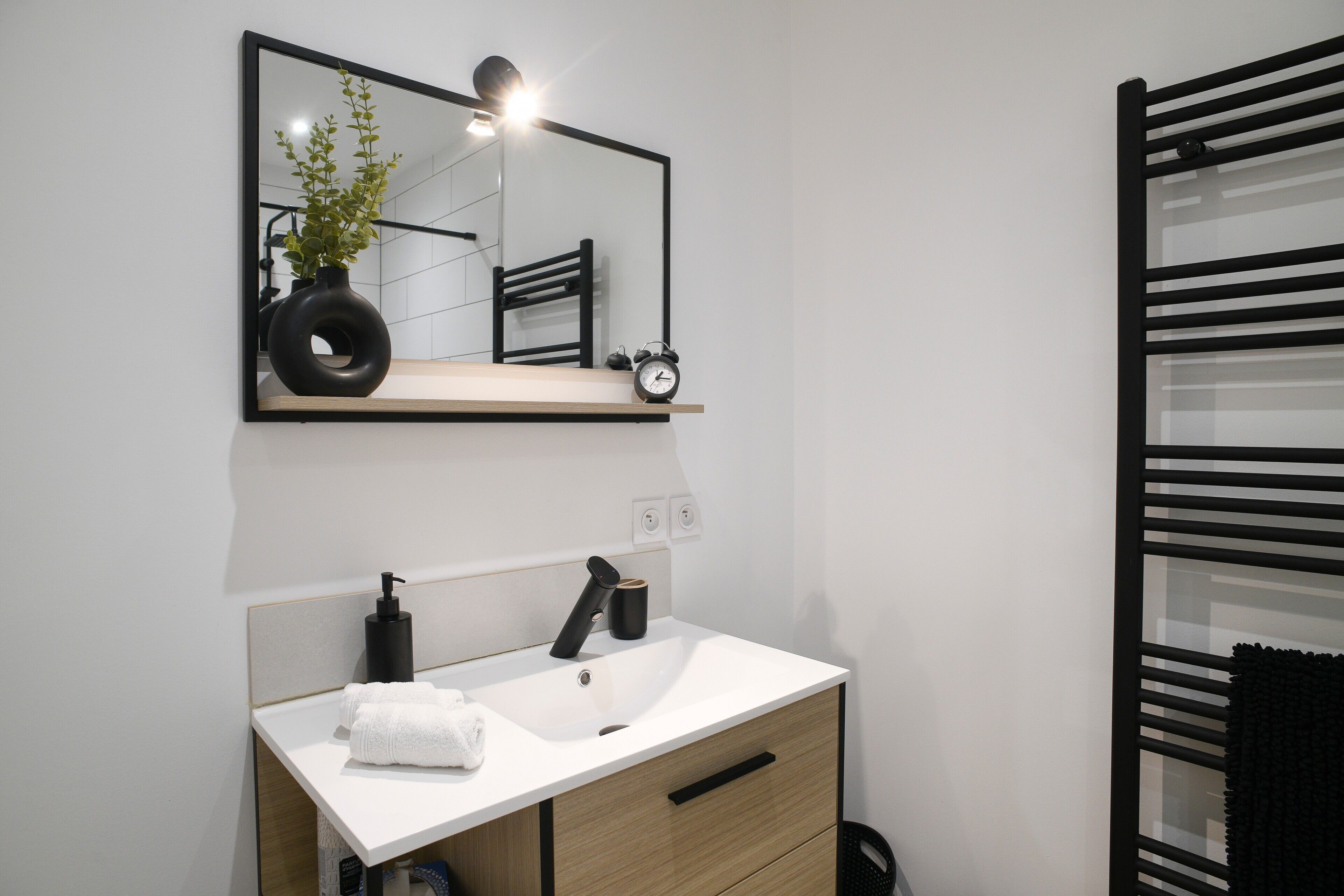 A modern bathroom with a white sink, black faucet, and a mirror above it.