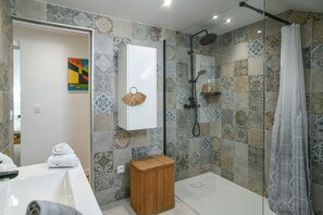Ein Badezimmer mit gemusterten Fliesen, einer Dusche, einer Toilette und einem Handtuchhalter.
